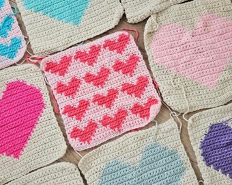 Puede incluir: Una colección de cuadrados de ganchillo con corazones de diferentes colores. Los cuadrados están hechos con hilo beige y presentan corazones rosas, azules, morados y un patrón de corazones rosas.