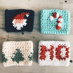 May include: Four crocheted coffee cup cozies with different Christmas designs. The cozies are in blue, green, white, and red.