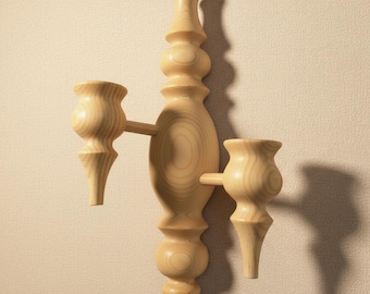 Puede incluir: Una lámpara de pared de madera de color claro con dos candelabros. La lámpara tiene una columna central ornamentada con una parte superior e inferior decorativas. Los candelabros se extienden horizontalmente y la lámpara está montada en una pared beige.