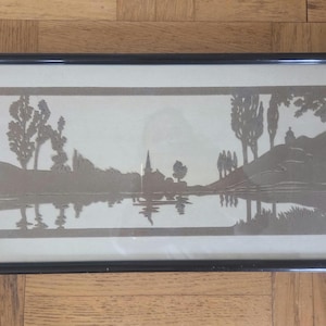 May include: Framed landscape art print featuring a serene waterscape with trees, a church, and hills. The artwork is in a monochromatic palette, with a black frame. The image reflects the scene below, creating a symmetrical composition.