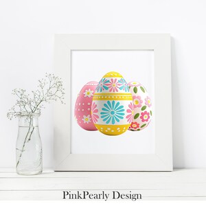 May include: A white framed print featuring three decorative Easter eggs. The eggs are painted with floral and geometric patterns in pink, yellow, and blue. The text "Pink Pearly Design" is at the bottom of the frame.