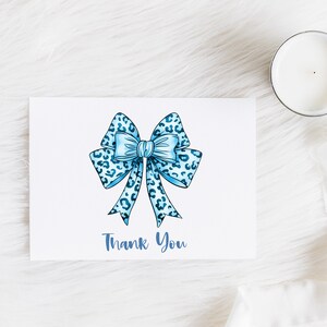 May include: A white card with a blue and white leopard print bow and the text "Thank You" in blue.