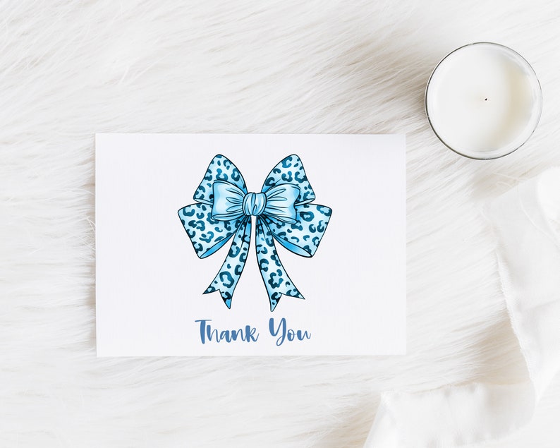 May include: A white card with a blue and white leopard print bow and the text "Thank You" in blue.