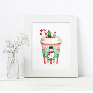 May include: A framed print featuring a festive holiday coffee cup design. The cup is adorned with a snowman, snowflakes, and a candy cane. The color palette includes red, green, and white, evoking a cozy winter theme.