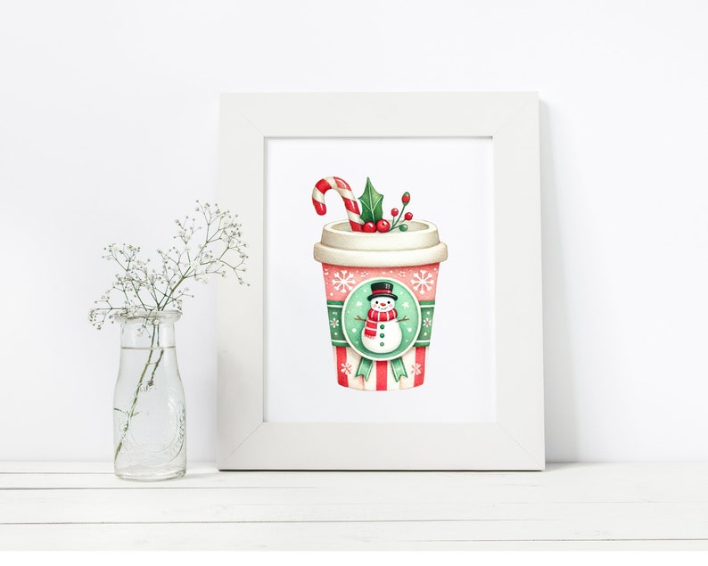 May include: A framed print featuring a festive holiday coffee cup design. The cup is adorned with a snowman, snowflakes, and a candy cane. The color palette includes red, green, and white, evoking a cozy winter theme.