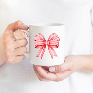 Puede incluir: Taza de cer&aacute;mica blanca con un dise&ntilde;o de lazo de acuarela rosa y blanco.