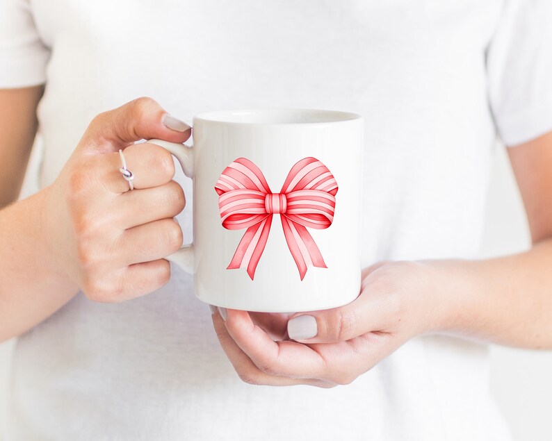 Puede incluir: Taza de cer&aacute;mica blanca con un dise&ntilde;o de lazo de acuarela rosa y blanco.