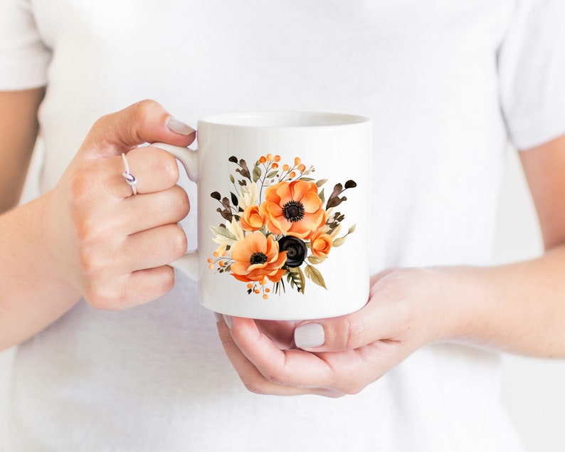 May include: White ceramic mug with a floral design featuring orange and black flowers. The flowers are watercolor style and have a vintage feel.