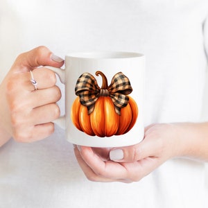 May include: White ceramic mug with a hand-painted orange pumpkin with a brown and black plaid bow.