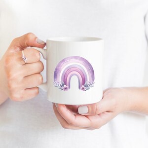 May include: White ceramic mug with a purple and pink watercolor rainbow design with flowers and leaves.