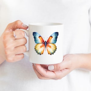 May include: White ceramic mug with a colorful butterfly design. The butterfly has blue, orange, and yellow wings.