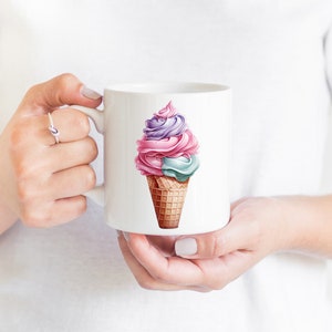 May include: White ceramic mug featuring a colourful ice cream cone design. The ice cream is pink, purple and blue with a waffle cone.