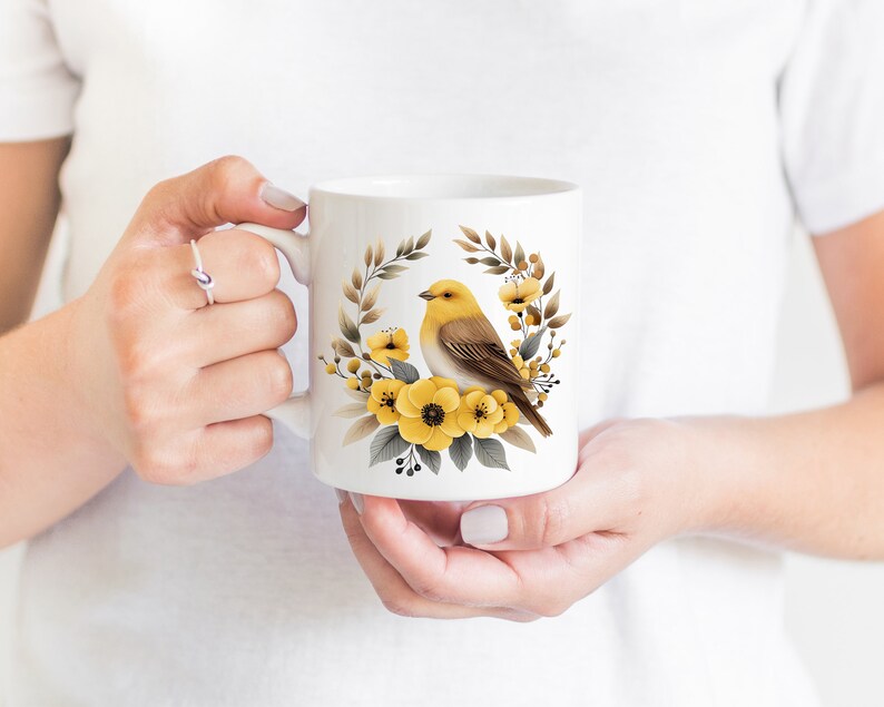 May include: White ceramic mug with a yellow bird and yellow flowers in a wreath design.