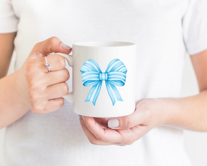 May include: White ceramic mug with a blue watercolor bow design.