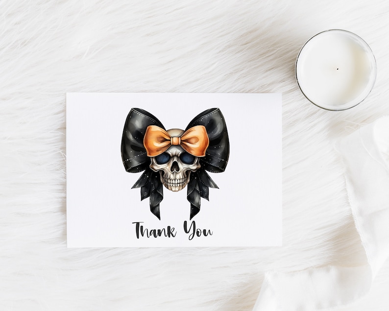 Pode incluir: Uma caveira branca com um la&ccedil;o preto e laranja. A caveira tem olhos pretos e um nariz preto. O la&ccedil;o est&aacute; amarrado em volta da cabe&ccedil;a da caveira. O texto "Thank You" est&aacute; impresso abaixo da caveira.