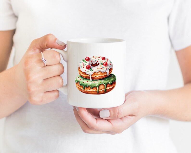 May include: White ceramic mug with a green and white donut with red sprinkles. The donut is stacked on top of another donut with white frosting and red sprinkles.