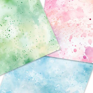 Op de afbeelding: Drie vellen aquarelpapier met abstracte splatterpatronen in tinten van groen, roze en blauw.