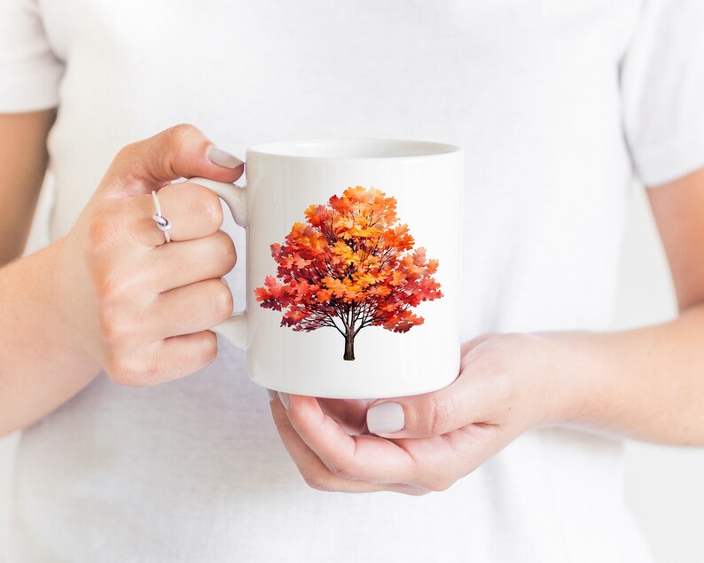 May include: White ceramic mug with a colorful autumn tree design. The tree has orange, red, and yellow leaves.