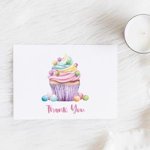 May include: A pink and white cupcake with rainbow frosting and colorful sprinkles. The cupcake is on a white background with the text "Thank You".