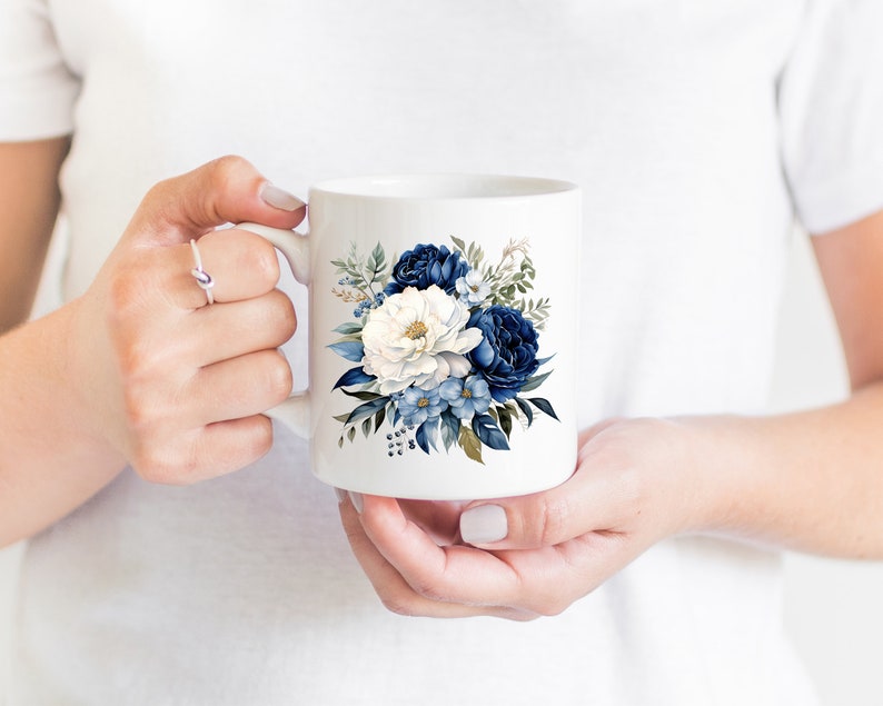 May include: White ceramic mug featuring a blue and white floral design. The flowers are a mix of blue and white peonies and smaller blue flowers.