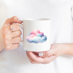 Puede incluir: Taza de cer&aacute;mica blanca con un dise&ntilde;o de nube de acuarela en tonos de rosa, azul y blanco.