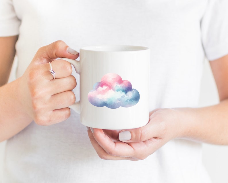 Puede incluir: Taza de cer&aacute;mica blanca con un dise&ntilde;o de nube de acuarela en tonos de rosa, azul y blanco.