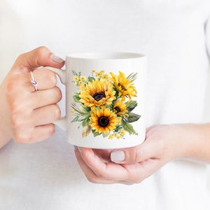 May include: White ceramic mug with a colorful watercolor design of sunflowers and greenery.