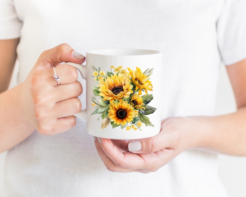 May include: White ceramic mug with a colorful watercolor design of sunflowers and greenery.
