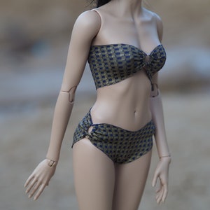 May include: A blue and gold patterned bikini top and bottom. The top is strapless and has a ring detail in the front. The bottom has a high-cut leg.