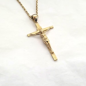 May include: A gold-tone chain necklace with a gold-tone crucifix pendant. The crucifix features a detailed figure of Jesus Christ.
