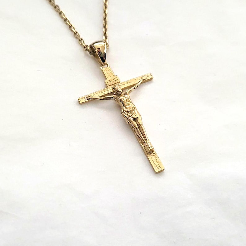 May include: A gold-tone chain necklace with a gold-tone crucifix pendant. The crucifix features a detailed figure of Jesus Christ.