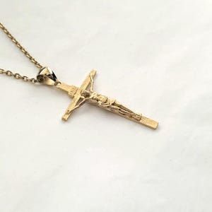 May include: A gold chain necklace with a gold crucifix pendant. The crucifix features a detailed depiction of Jesus Christ.