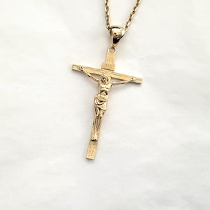 May include: A gold-toned crucifix pendant with a detailed figure of Jesus Christ. The pendant is attached to a gold chain.