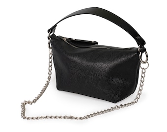 Può includere: Borsa a mano in pelle nera con tracolla a catena argentata. La borsa ha una chiusura a zip e un manico superiore.