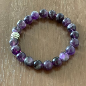 May include: A purple amethyst beaded bracelet with a silver spacer bead.