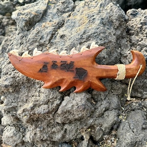 May include: A wooden carving of the Hawaiian islands, with each island labeled. The carving is shaped like a traditional Hawaiian weapon, with a sharp point and a curved handle. The carving is brown and has a natural wood finish.