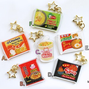 以下が含まれることがあります： インスタントラーメンのキーホルダーチャームが10種類。それぞれ異なるラーメンの味が特徴で、チキン、スパイシー、ミーゴレンなどがあります。チャームは透明なアクリル製で、キーホルダーに取り付けるための金色の金属リングが付いています。