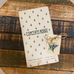 Op de afbeelding: Een vintage concertprogramma voor Concerts-Rouge in Parijs, Frankrijk. Het programma heeft een bijenpatroon en de tekst "SAISON 1909-1910 Direction, G. RABANI."