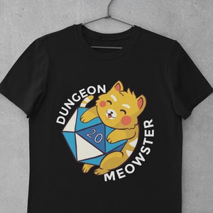 May include: Black t-shirt with a yellow cat holding a blue and white 20-sided die. The text "Dungeon Meowster" is written in a circle around the cat.