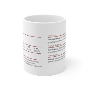 May include: White ceramic mug with brown text describing a character's actions, bonus actions, and reactions. The text includes the words "Helping Hand", "Bestie Hug", and "Shield".