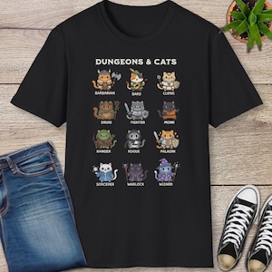 May include: Black t-shirt featuring the text "DUNGEONS & CATS" above illustrations of cats as fantasy characters, including a barbarian, bard, cleric, druid, fighter, monk, ranger, rogue, paladin, sorcerer, warlock, and wizard.