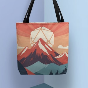 May include: Tote bag featuring a mountain landscape with a large, white, geometric shape resembling a die. The design includes red, blue, and green mountains, a setting sun, and black handles. The bag is made of fabric.