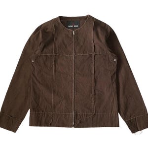 May include: A brown jacket with a zip-up front and long sleeves. The jacket has a unique design with visible stitching and a textured appearance. The brand name "RAPHAEL MILLER" is visible on the collar.
