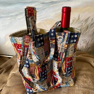 May include: A double wine bottle tote bag with a patriotic print featuring stars, stripes, and the words "Liberty and Justice for All." The bag is made of fabric and has two compartments, each holding a wine bottle.