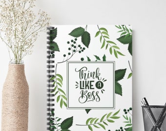 May include: A white spiral notebook with a green leafy pattern and the text "Think Like A Boss" in black lettering.