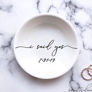May include: White ceramic ring dish with the text "i said yes" and the date "7-21-19" in black script.