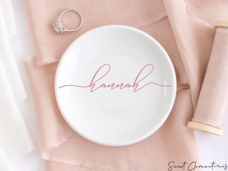 May include: White ceramic ring dish with the name "Hannah" written in pink cursive script.