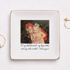 Puede incluir: Plato de cer&aacute;mica blanco con borde dorado, con una fotograf&iacute;a de dos ni&ntilde;as peque&ntilde;as abraz&aacute;ndose. El plato tiene el texto "To my best friend, my big sister and my role model. I love you!"