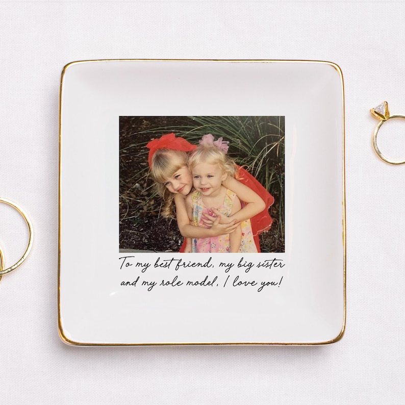 Puede incluir: Plato de cer&aacute;mica blanco con borde dorado, con una fotograf&iacute;a de dos ni&ntilde;as peque&ntilde;as abraz&aacute;ndose. El plato tiene el texto "To my best friend, my big sister and my role model. I love you!"