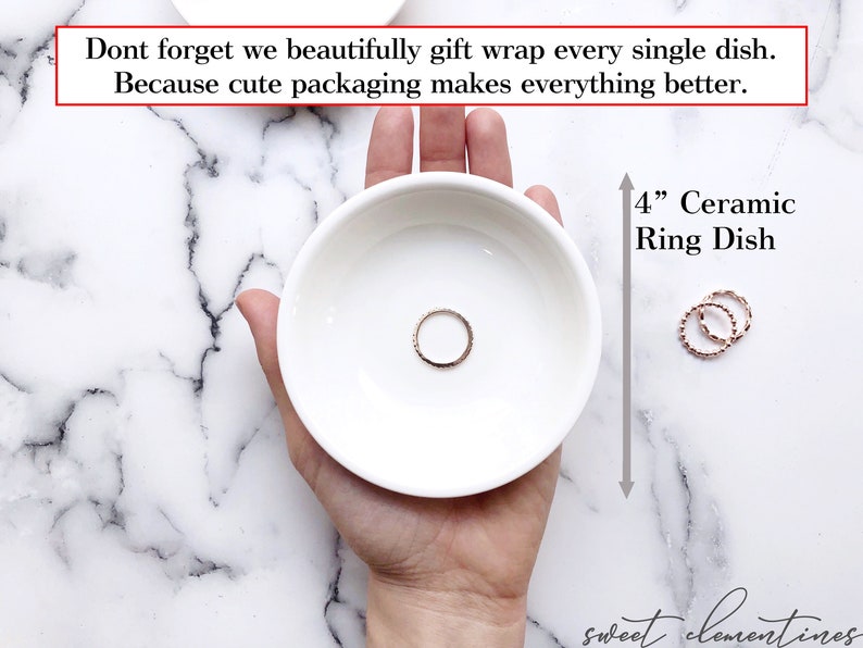 May include: A white ceramic ring dish, 4 inches in diameter, with a gold ring inside. The dish is being held in a hand against a white marble background. The text "4" Ceramic Ring Dish" is written in black on a white background.